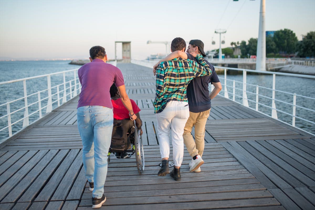 Group of friends walking along a scenic boardwalk, including a wheelchair user